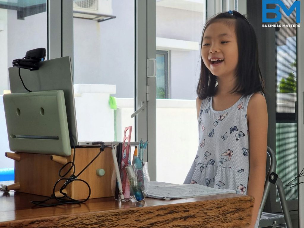 future of learning, a kid girls is learning online standing and laughing in front of laptop, showing future of learning